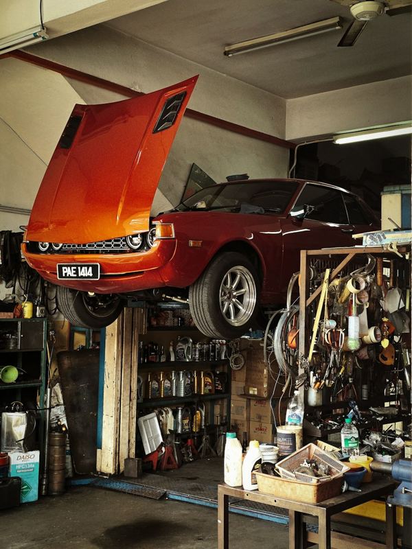 A classic car up on a lift in a repair shop